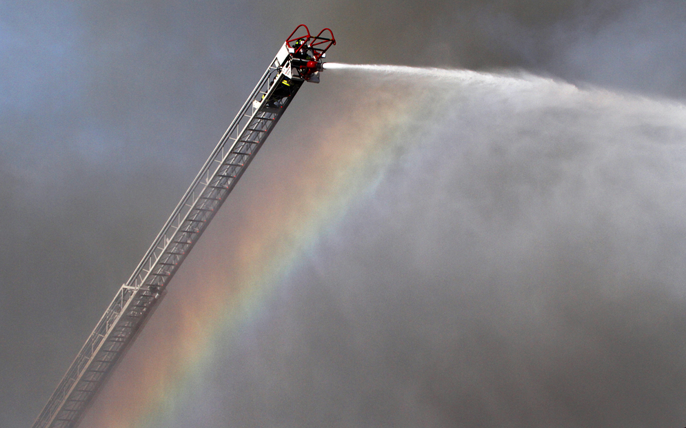 A lone firefighter mans a ladder while battling a  multi-alarm fire at the C-Town supermarket, Monday, April 13, 2015, in South Amboy, NJ.